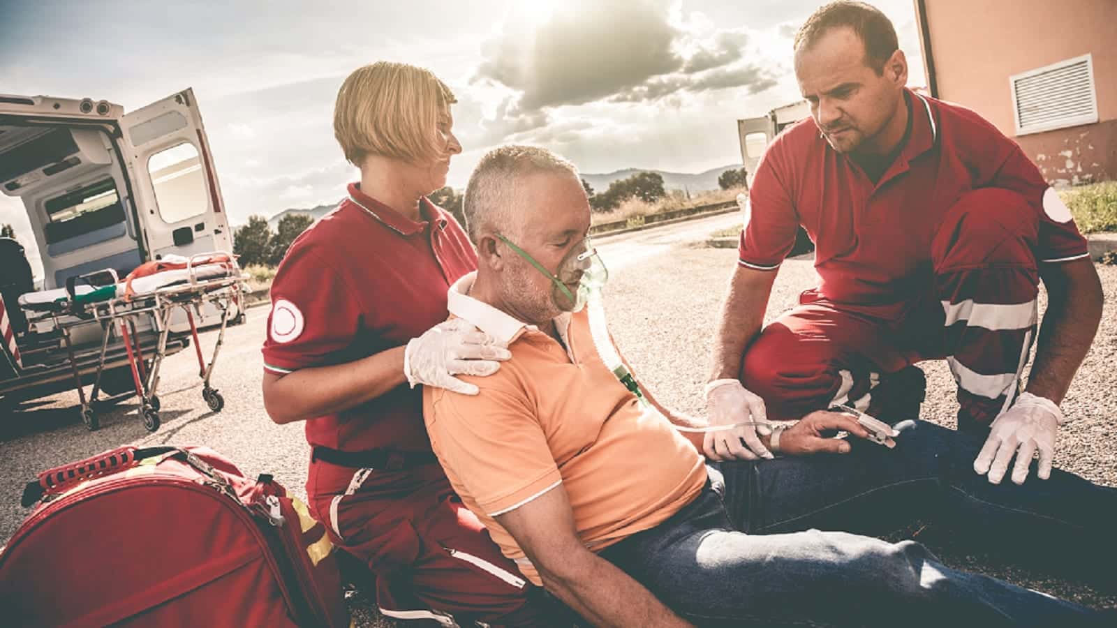 Paramedics attending to elderly man with oxygen mask, addressing pre-existing injury aggravated in car accident