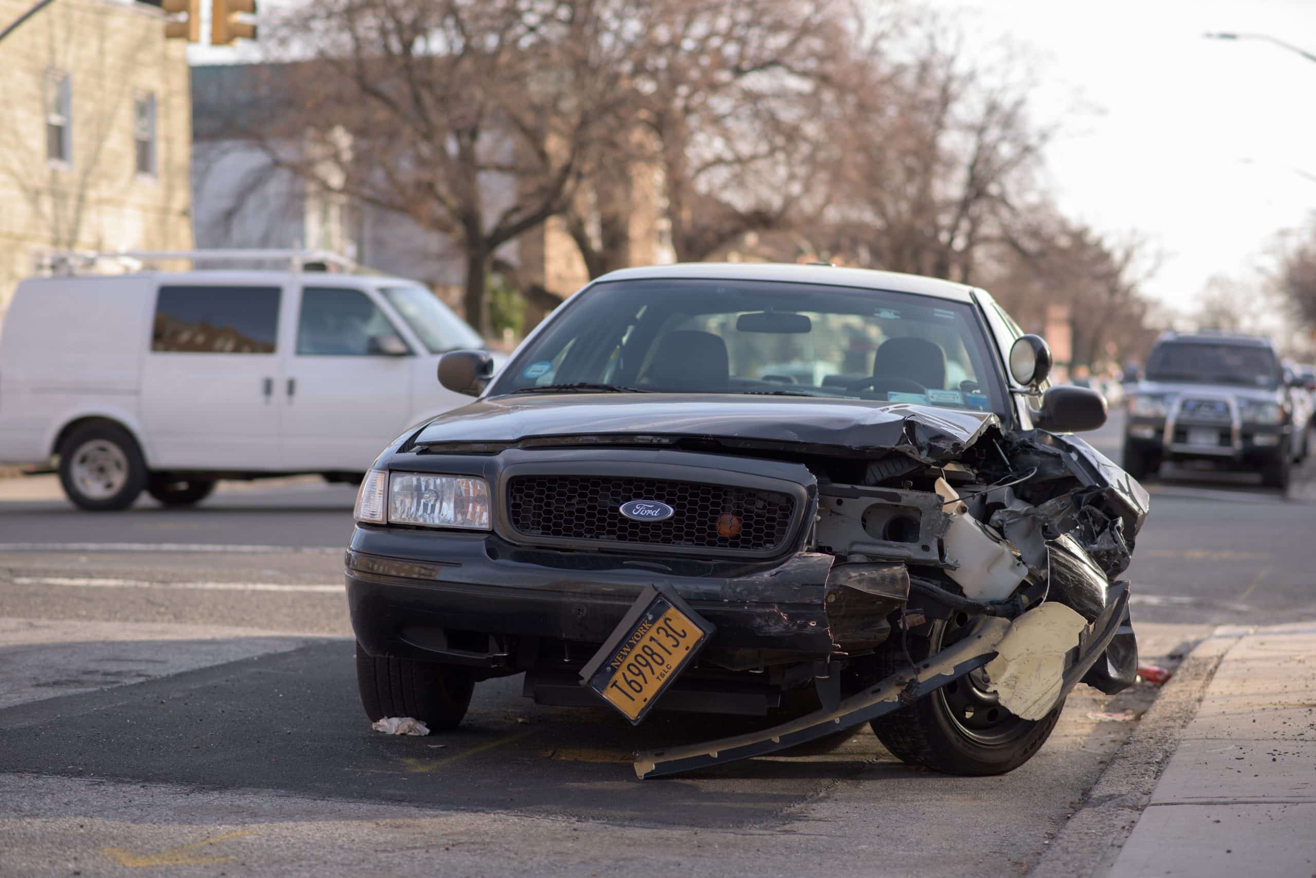 Car accident, car, pavement, tree, building.