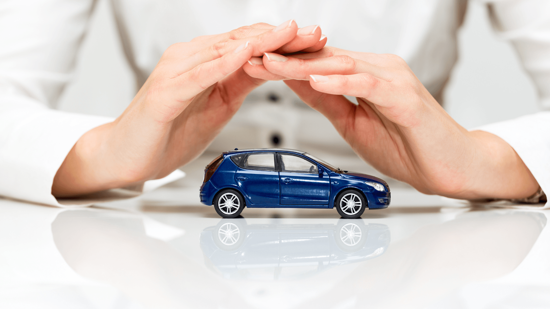 Auto insurance attorneys hand covering a toy car